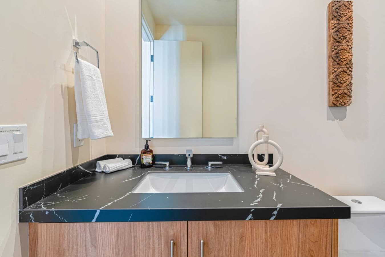 Polished bathroom w/ stone countertop, large mirror, and an airy, well-lit layout.