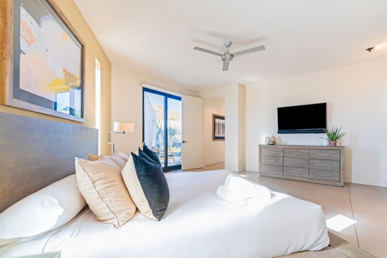 Airy bedroom w/ wood dresser, cozy textures, and sliding doors bringing the outdoors in.