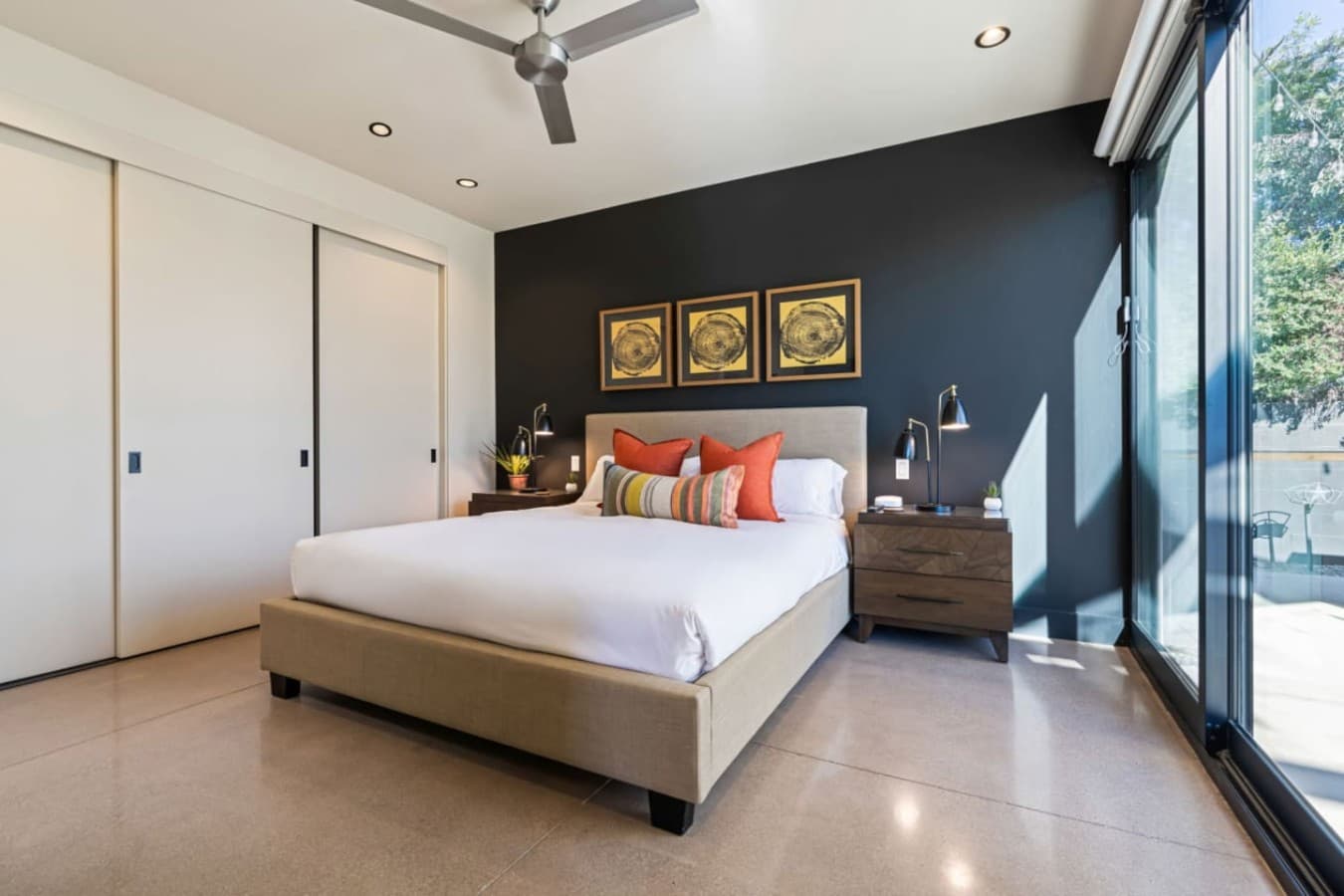 Modern bedroom w/ dark accent wall, warm pillows, and a calm, cozy vibe.