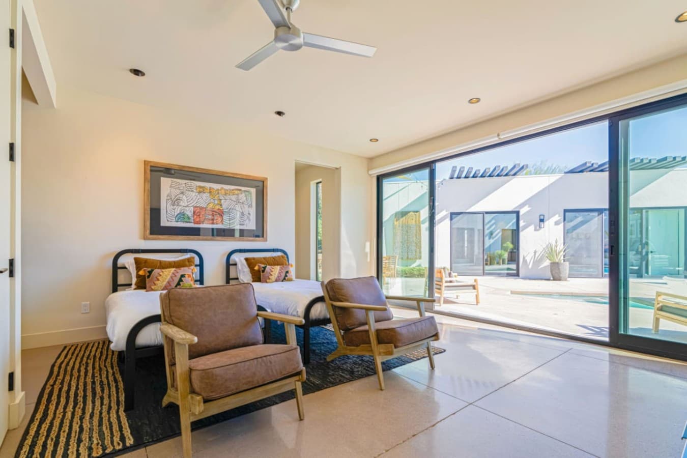 Lounge-style seating area w/ plush chairs and glass doors opening to the pool courtyard.