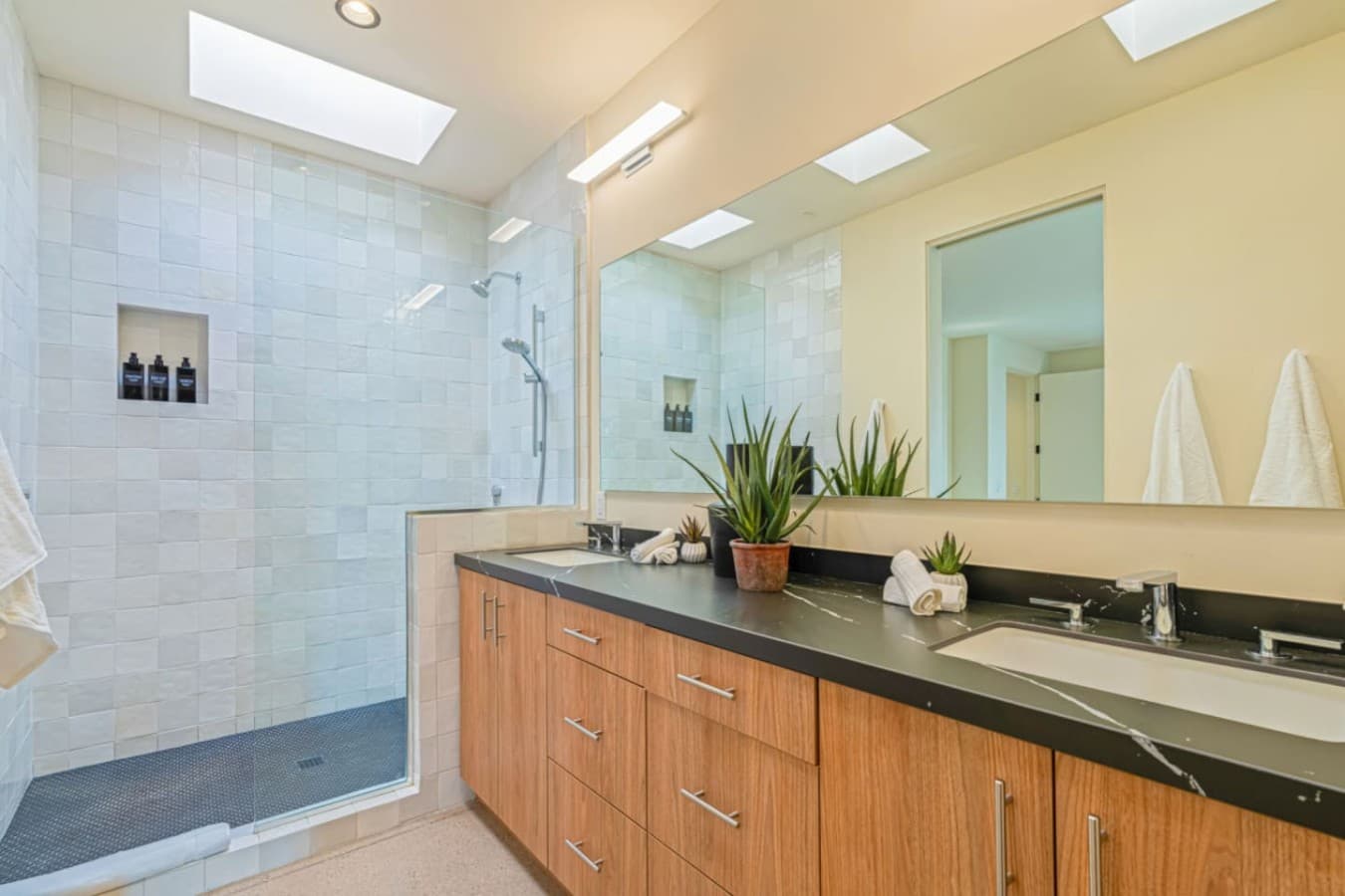 Clean double vanity w/ stone counters, wide mirrors, and space to get ready together.