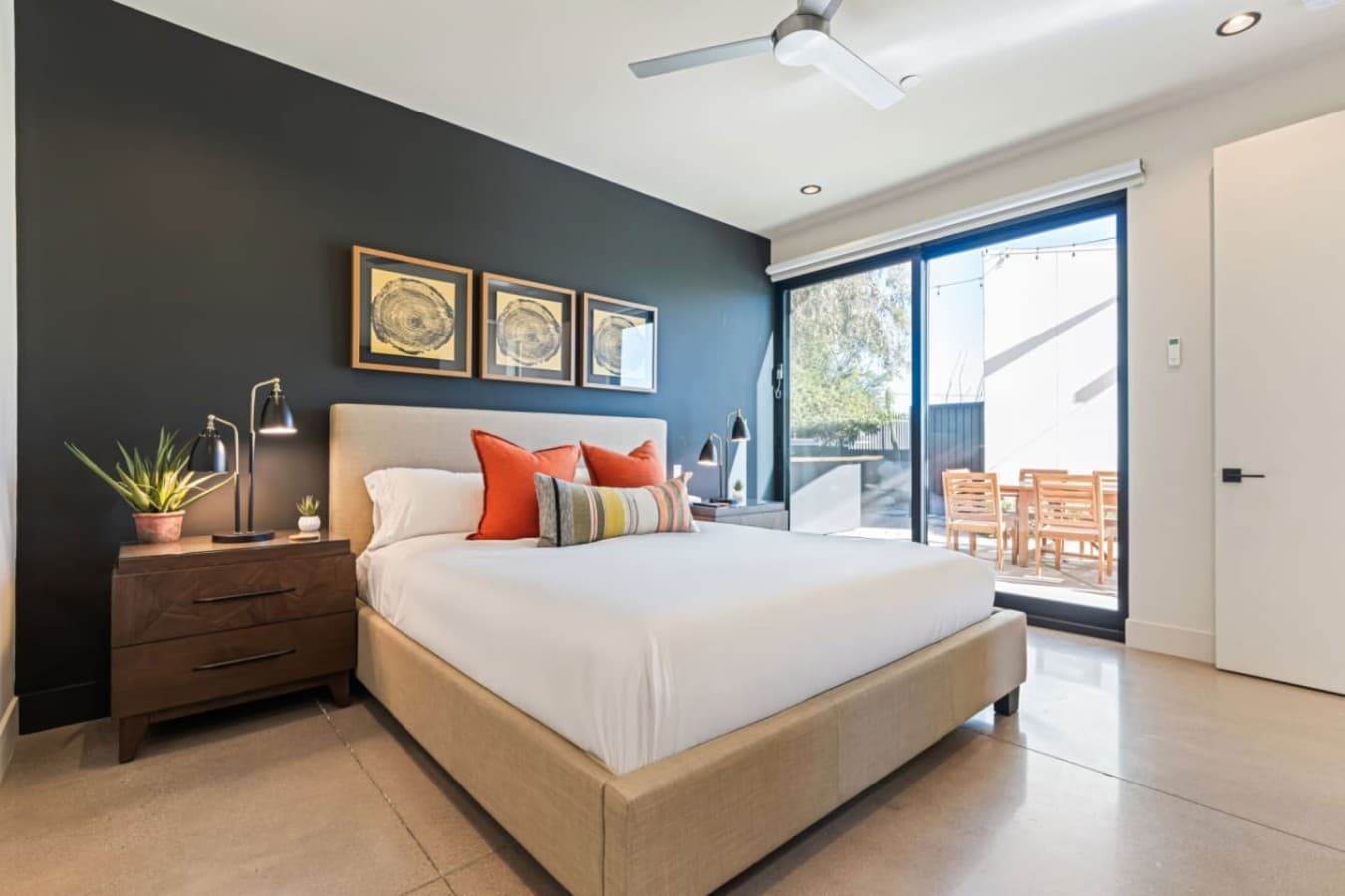 King bedroom w/ bold accent wall, plush pillows, and sliding doors opening to the sunny courtyard.