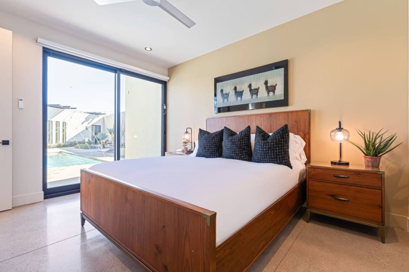 Warm, minimalist bedroom w/ wood bed frame, soft lighting, and a calm, uncluttered layout.