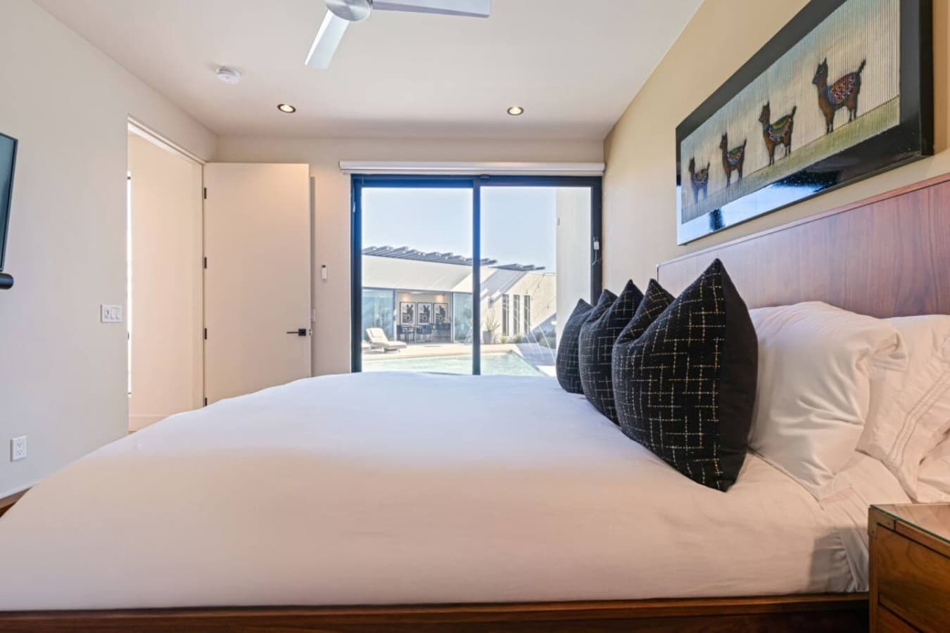 Bright bedroom w/ crisp linens, modern art, and easy access to the outdoor space.