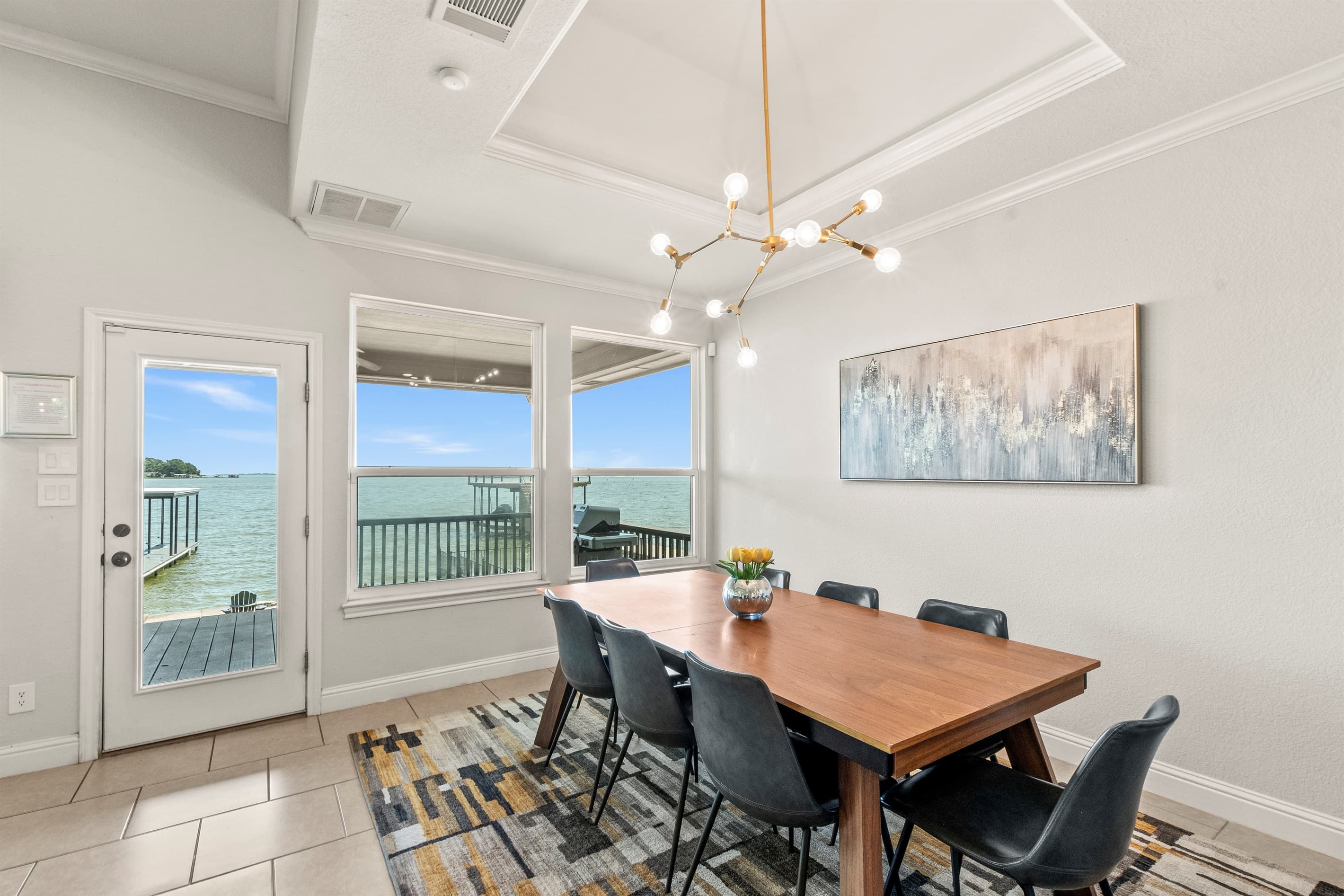 Bright and airy dining area flooded with natural light from large windows, perfectly framing serene water views.