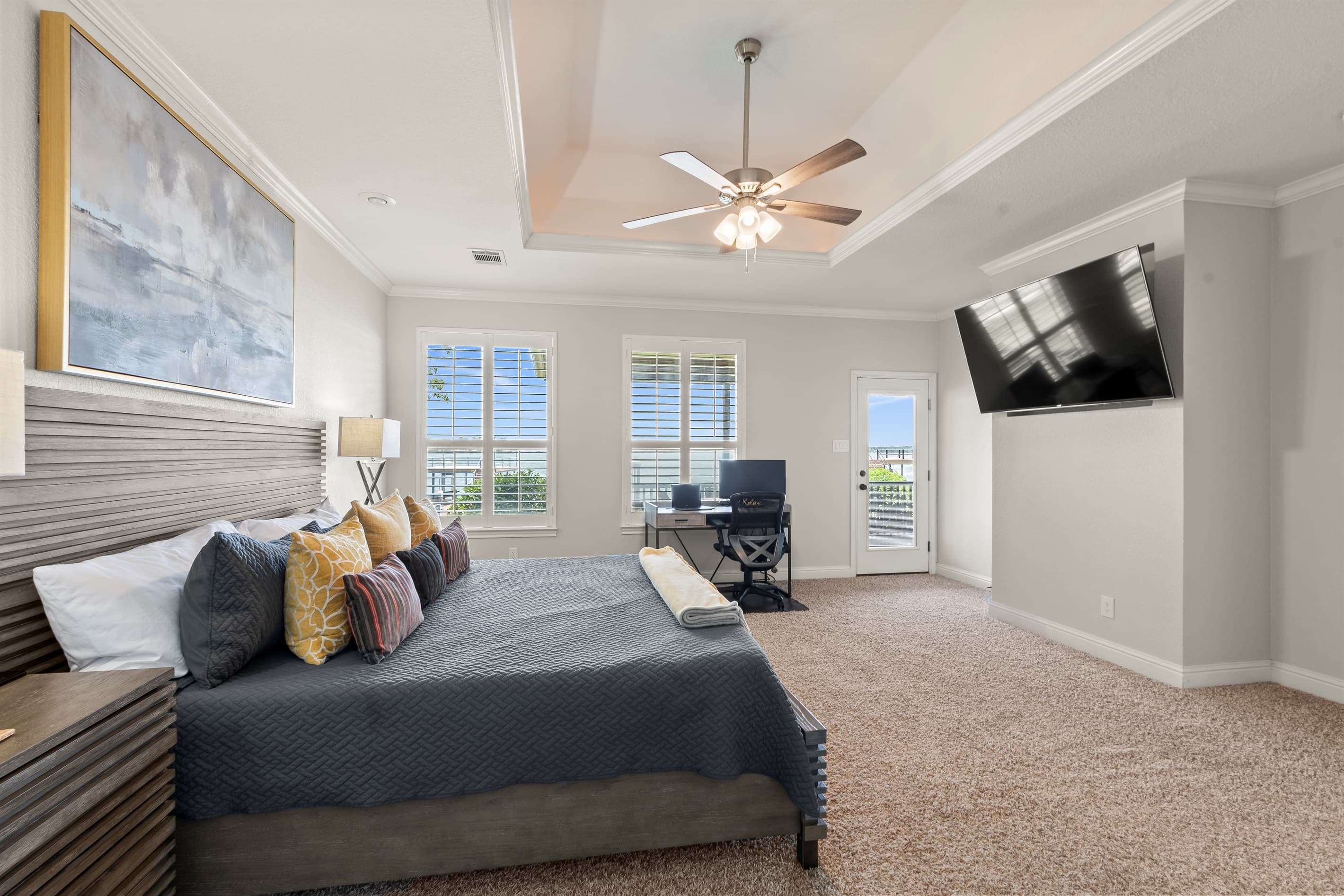 Spacious main bedroom with a dedicated workspace overlooking the lake through elegant shutters. Enjoy seamless remote work, direct access to the back porch, and unwind with a 65” Smart TV loaded with all your favorite streaming channels.