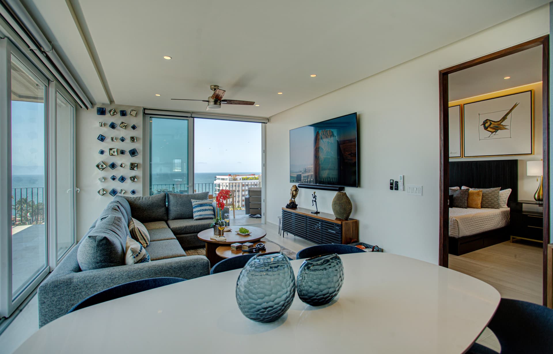 Unwind in the spacious living room featuring an 85” TV and floor-to-ceiling sliding doors that open to ocean breezes and endless, breathtaking views.