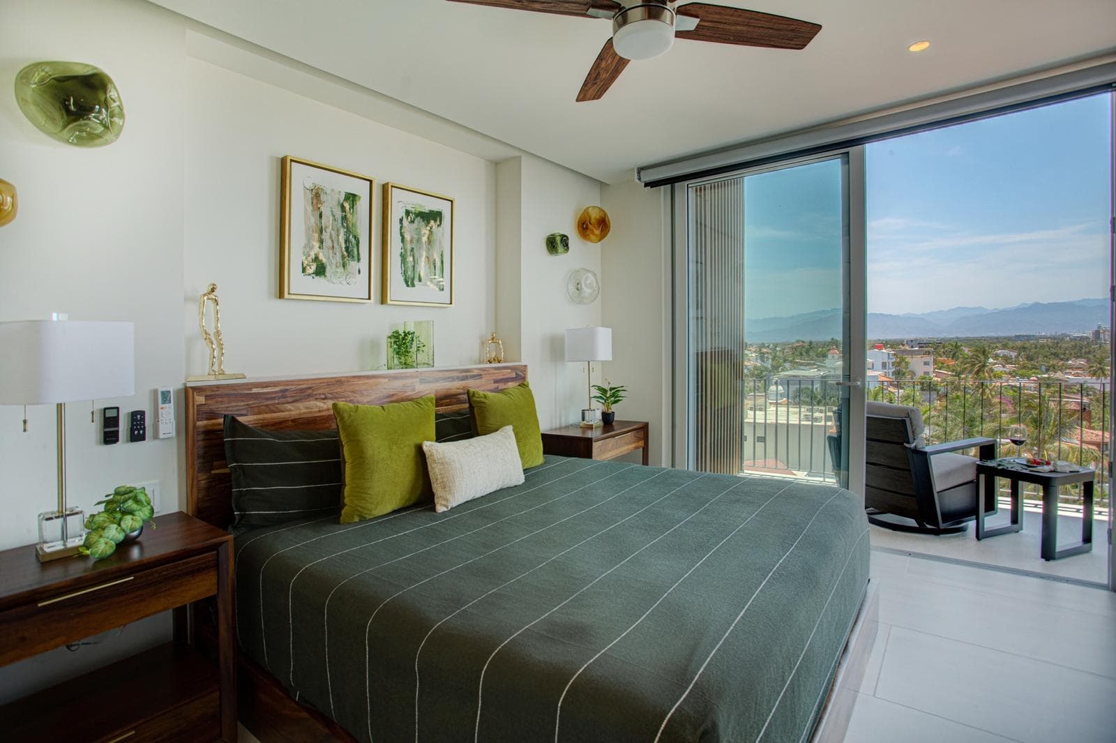 Spacious guest bedroom (#1) with ensuite bath, 65” streaming TV, generous closet and storage space, and private access to one balcony plus shared access to another—perfect for relaxing in swivel chairs with a book and enjoying ocean views.