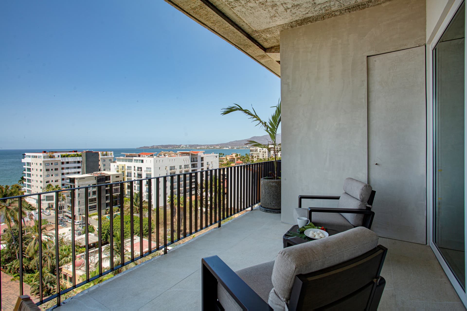 The large wraparound balcony is a standout feature with stunning ocean and mountain views and dining seating for 8.  To the right of the table is a cozy seating area perfect for morning coffee just off the primary bedroom or taking in the sunset.