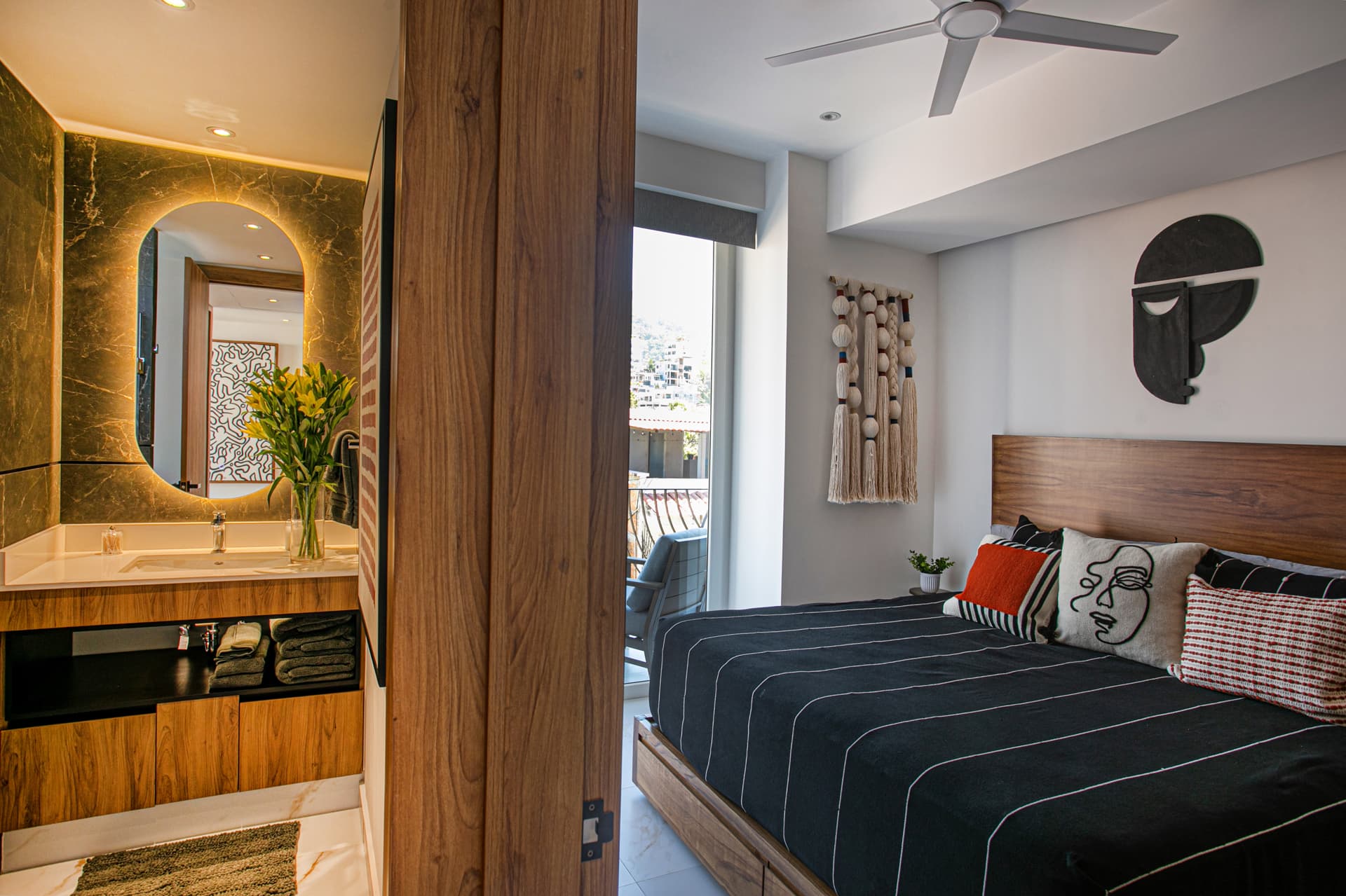 Guest bedroom with balcony and stunning views, plus an adjacent full-size bathroom featuring a rainshower, wall shower, hand wand, and a bench for added comfort.