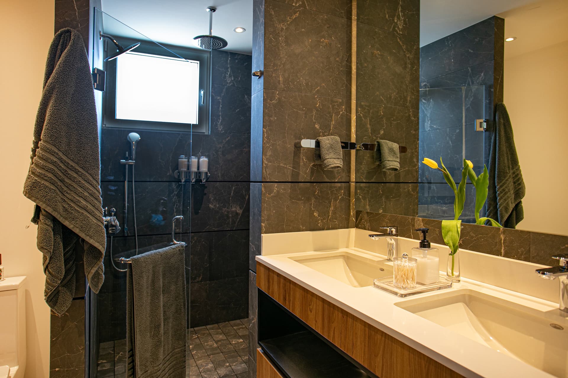 Primary bathroom featuring a double sink, double wall showers - a rain shower, a regular shower and two hand wand showers - perfect for two people to shower comfortably at the same time.