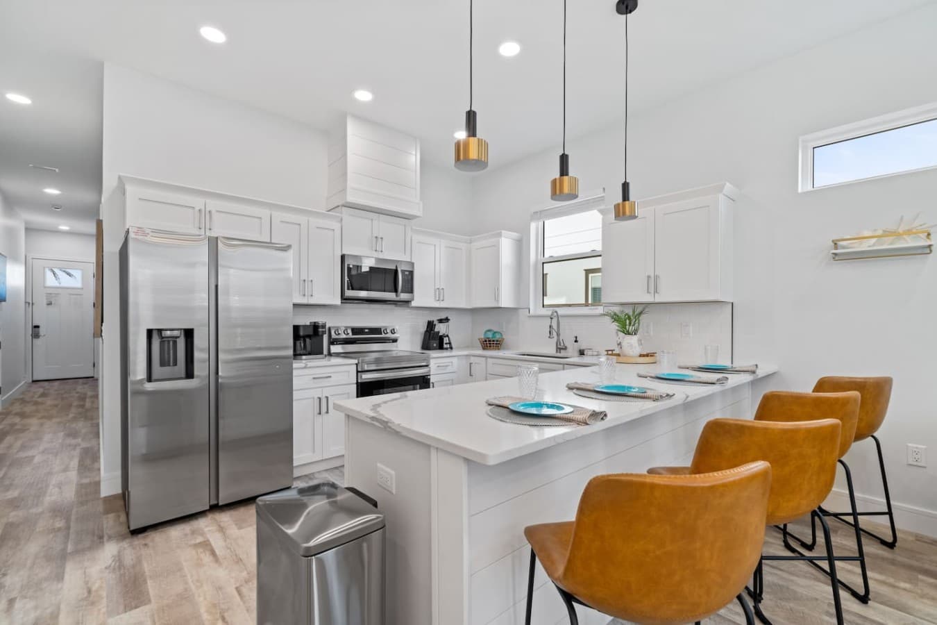 A modern kitchen with a bar for seating as well as stainless steel appliances