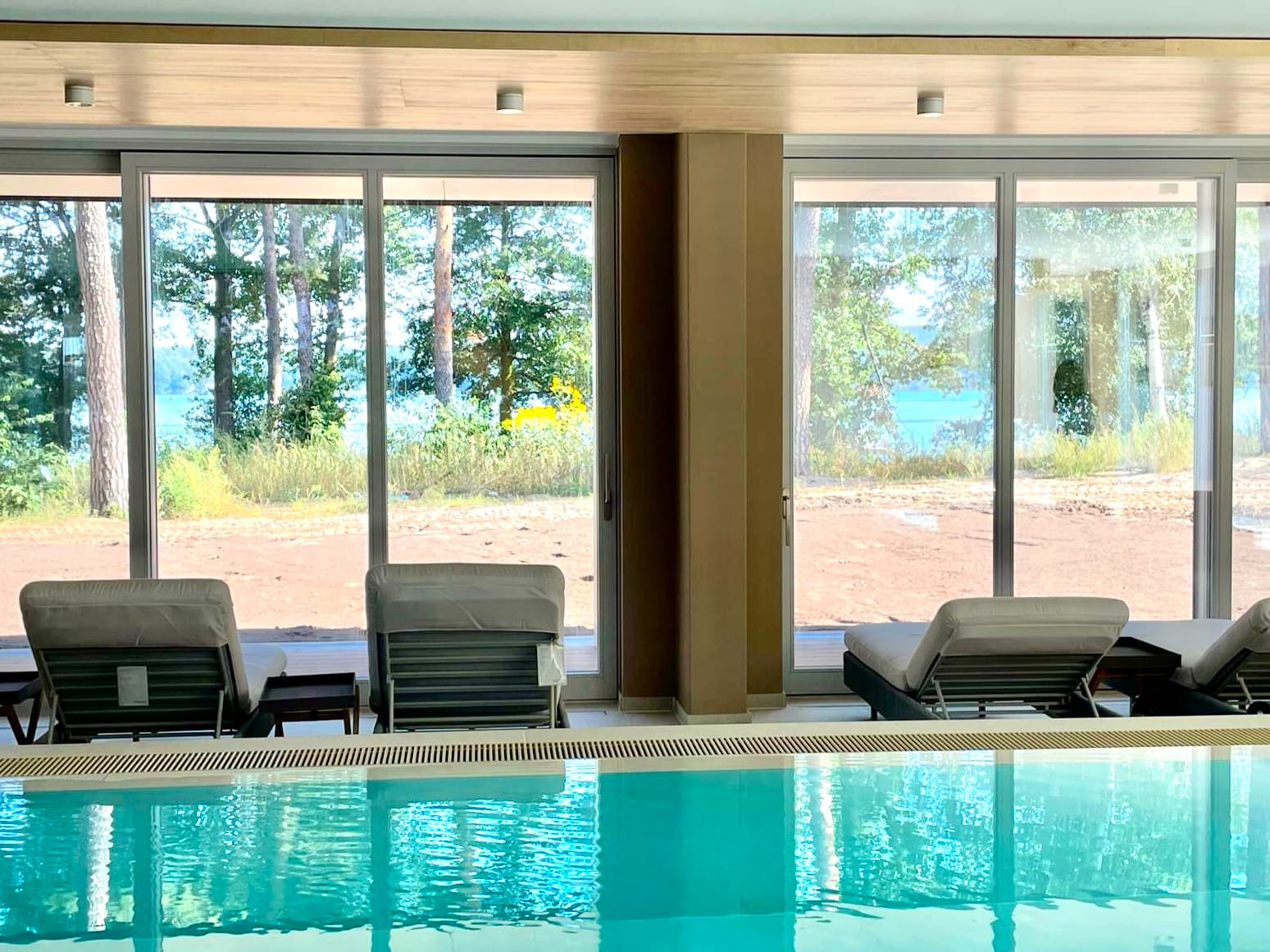 Pool mit Loungeliegen und Blick auf den See