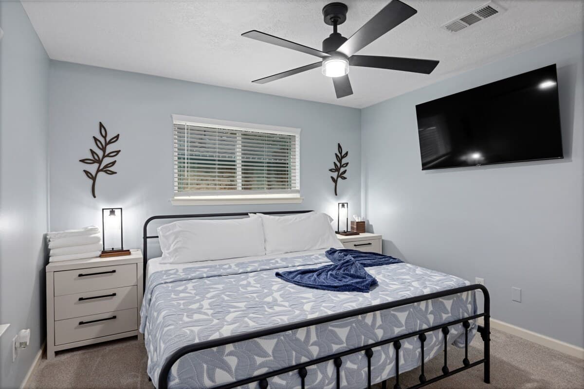 Calm primary bedroom with a king bed, ceiling fan, and 55" TV—designed for restful nights and easy relaxation.