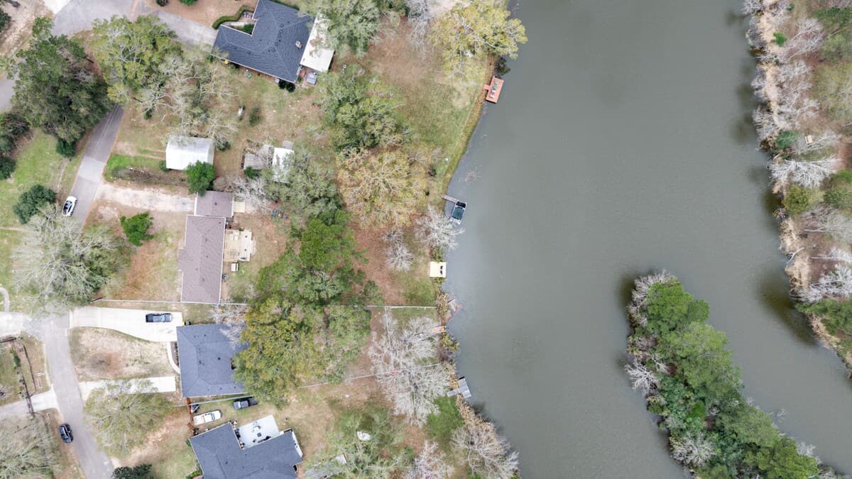 Alternate aerial angle highlighting the home’s waterfront setting, nearby docks, and tree-lined shoreline.