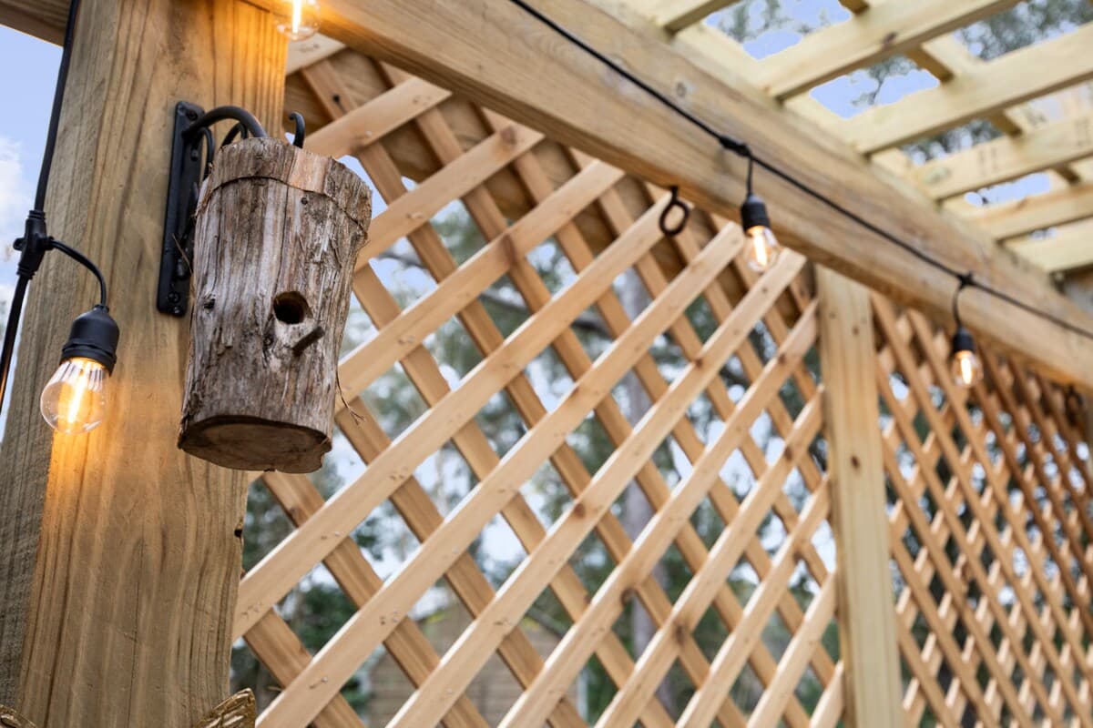 Outdoor space featuring a bird feeder, string lighting, and rustic wood accents for relaxed evenings.