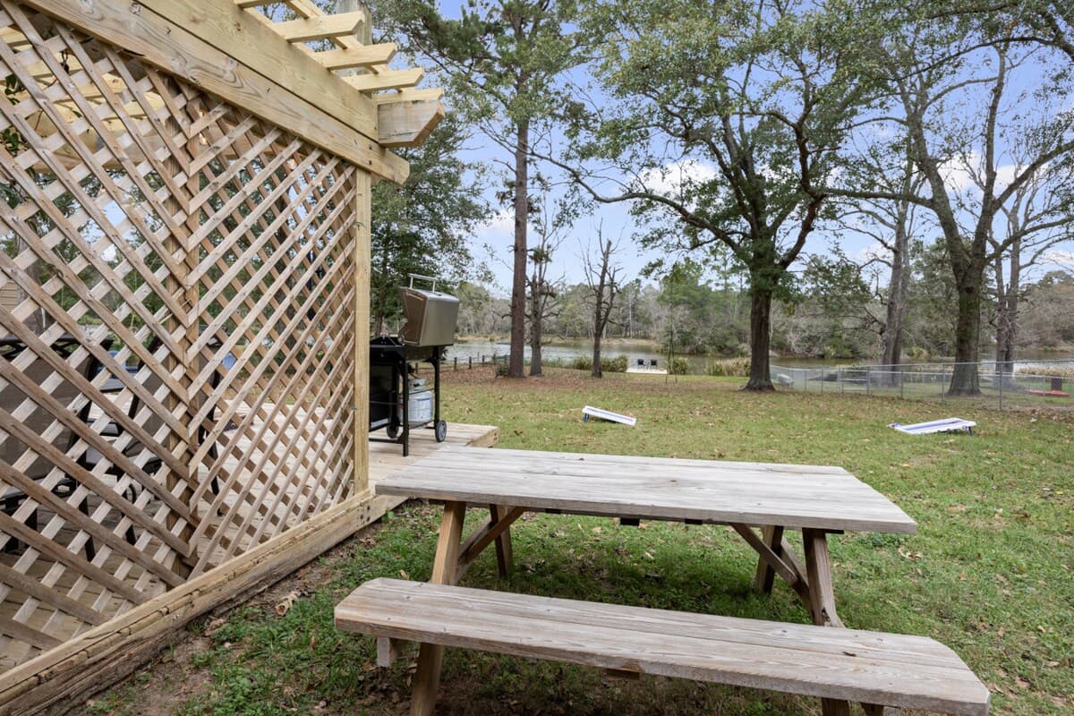 Rustic picnic table set in a spacious backyard with trees and lake views.