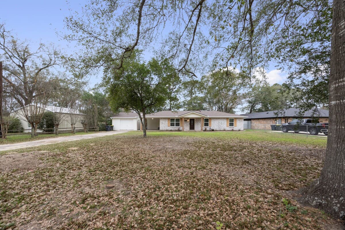 Expansive front yard framed by mature trees, offering a quiet, open setting with a clear view of the home and surrounding space.
