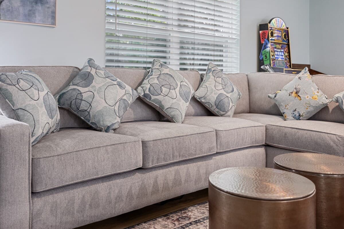 Spacious living room sectional that converts to a queen sleeper, styled with plush pillows and warm accents for lounging or extra sleeping space.