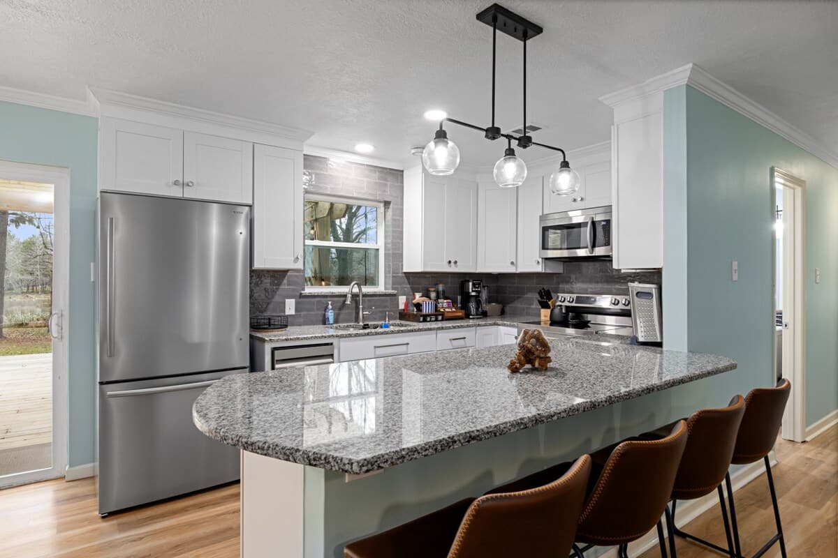 Modern kitchen with a large granite island, stainless appliances, and bar seating—ideal for cooking, gathering, and casual dining.