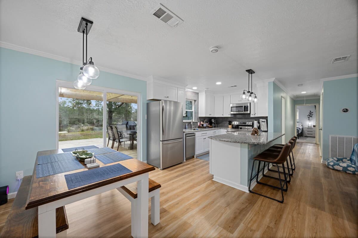 Open dining and kitchen area with island seating, modern finishes, and sliding doors leading to the outdoor pergola.