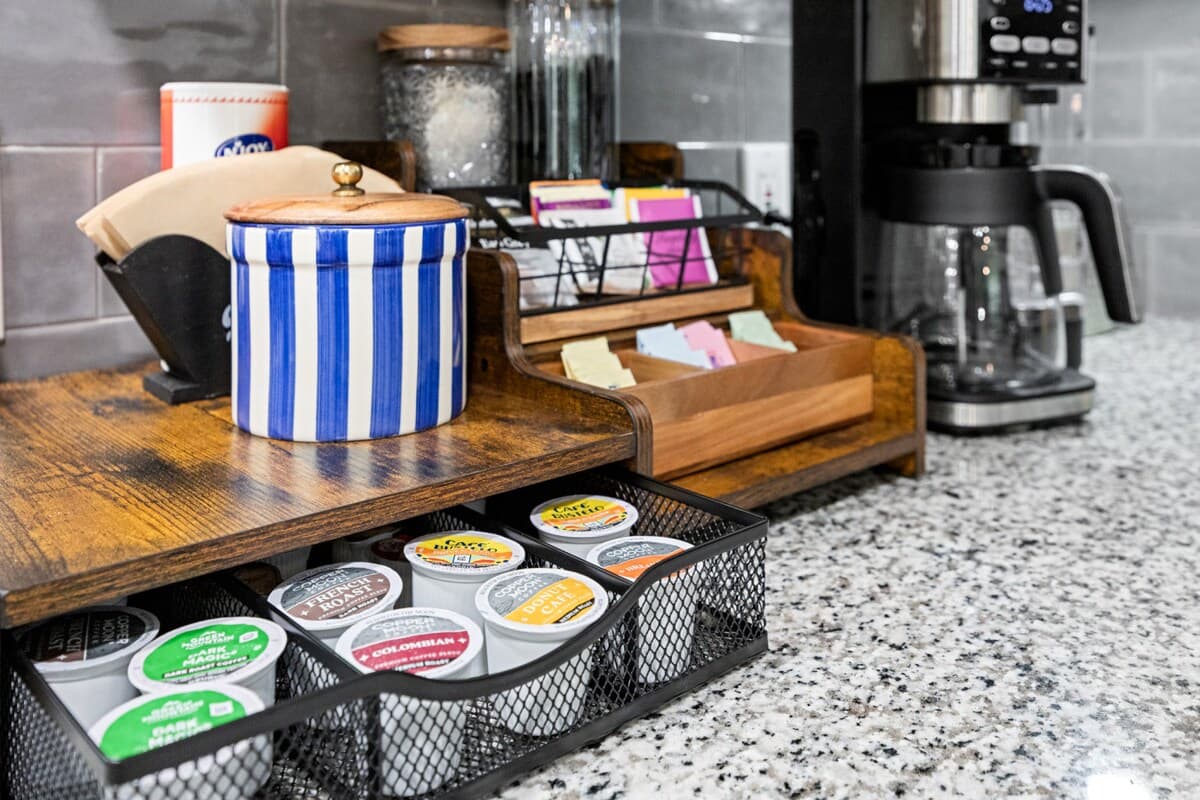 Well stocked coffee station with drip maker, assorted pods, sweeteners, mugs, and easy grab supplies for relaxed mornings.