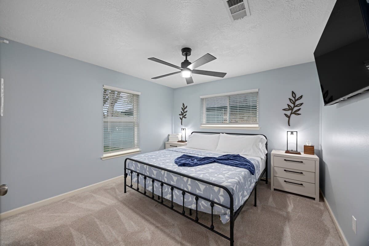 Spacious retreat featuring a king-size bed, ceiling fan, and 55" TV—offering a comfortable place to recharge and unwind.