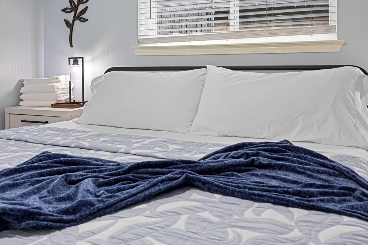 Cozy close-up of the king bed with crisp linens, plush pillows, and soft lighting for a restful night’s sleep.