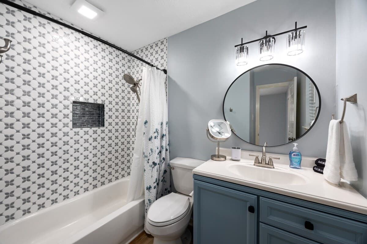 Ensuite bath connected to the primary bedroom, featuring a tub/shower combo, patterned tile, and a modern vanity.