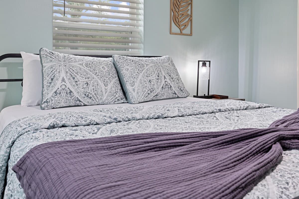Inviting queen bed dressed in soft linens and calming tones, creating a comfortable and welcoming place to unwind.