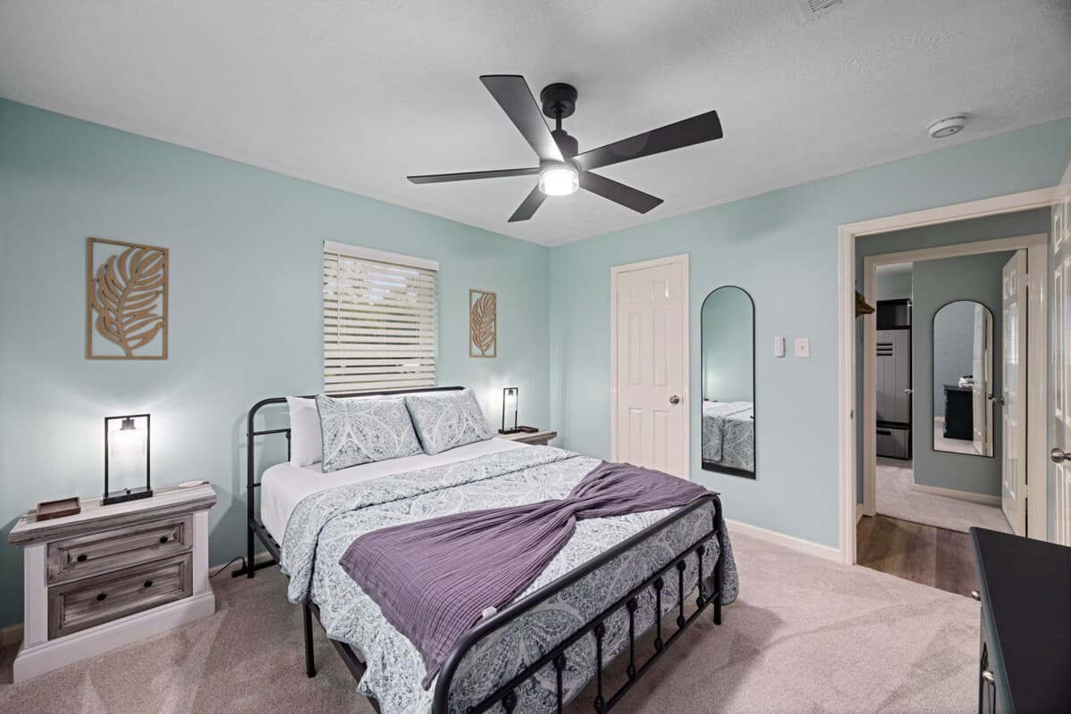Bright guest bedroom with soothing colors, ceiling fan, nightstands, and a clean, comfortable layout for a restful stay.