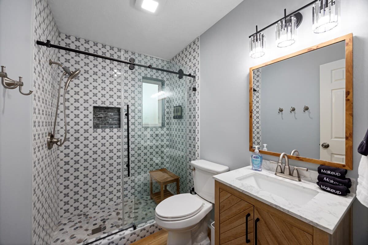 Full bathroom with a walk-in glass shower, patterned tile, and a modern vanity, offering a clean and refreshing space to start or end the day.