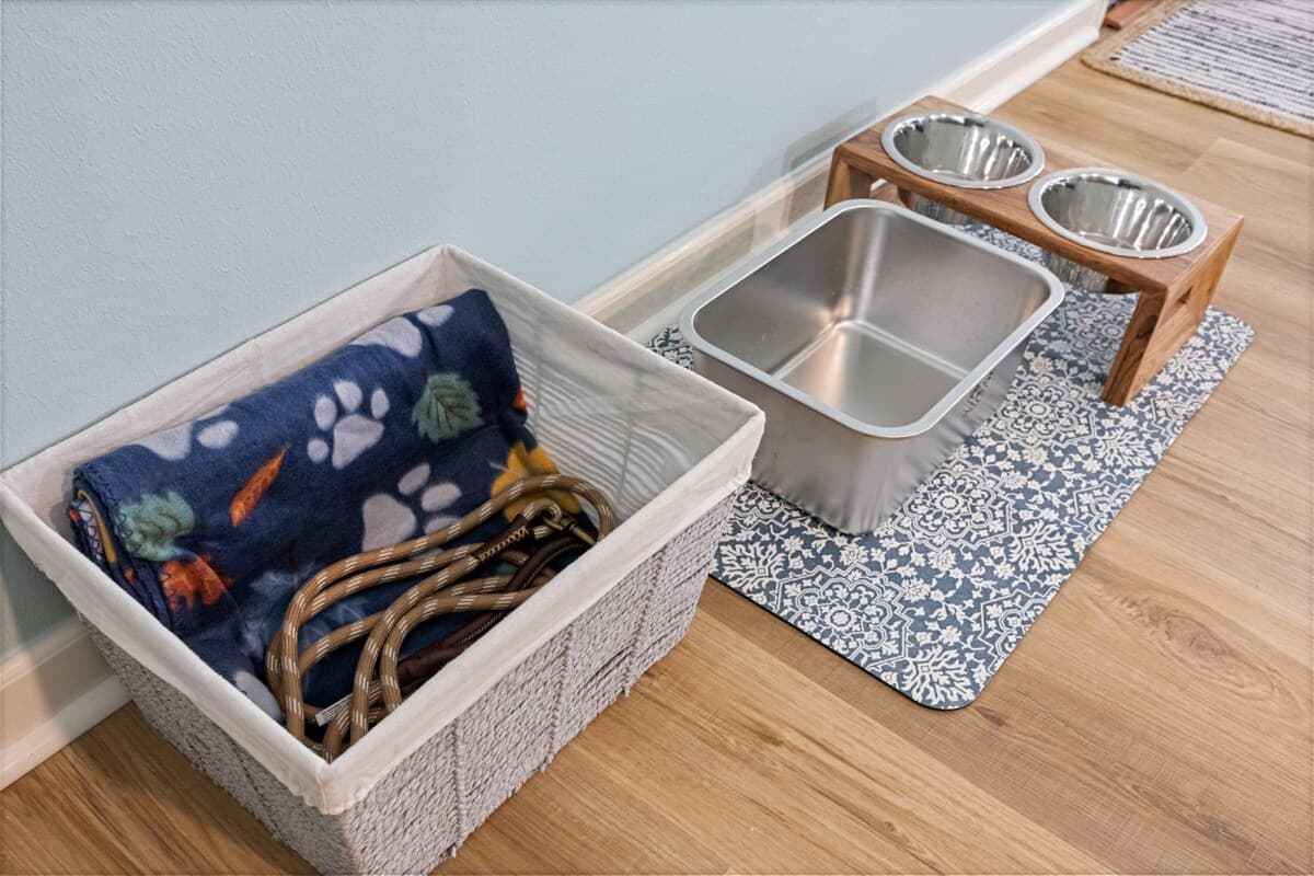 Pet-friendly setup – elevated food & water bowls, leash storage, and cozy blanket on a protective mat.