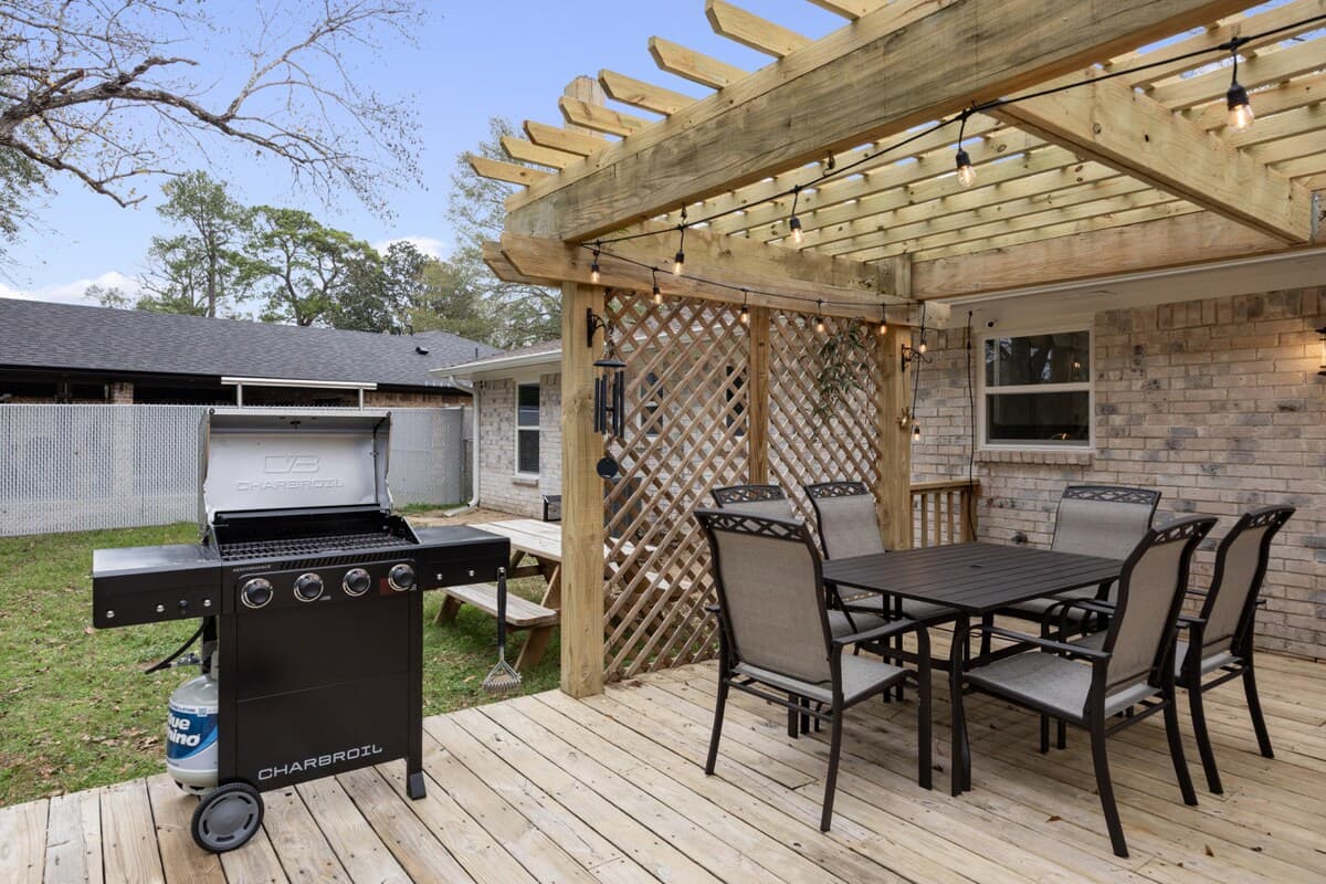 Set up for comfort and convenience, this covered deck includes a dining table, string lights, and a grill, creating a natural extension of the home where meals and memories come together.