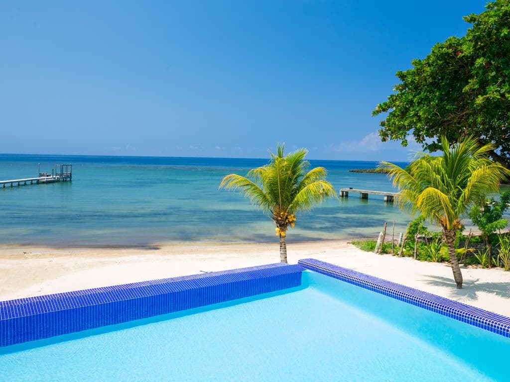 Experience the ultimate horizon where the crystal-clear pool meets the turquoise Caribbean. Bathed in the bright island sun, our infinity edge offers an unobstructed, sparkling daytime view of paradise. ☀️🌊🌴