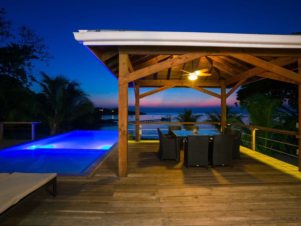 An evening shot of the dining area at Vivaro Roatan captures the transition from a fiery sunset to the sophisticated "Blue Hour." As the sky turns a deep indigo, the villa transforms into a glowing sanctuary.