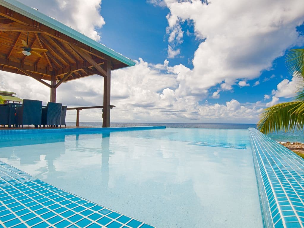 The Seamless Edge: As you float in the pool, the infinity edge drops away visually, aligning the pool's water line perfectly with the Caribbean Sea. From your perspective in the water, the boundary disappears entirely.