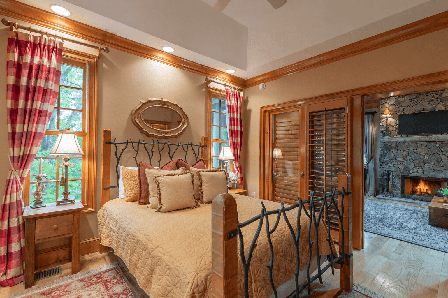 The cozy main-level queen bedroom offers warm mountain charm, wooded views, and easy access to the inviting living room with its stunning stone fireplace just steps away.