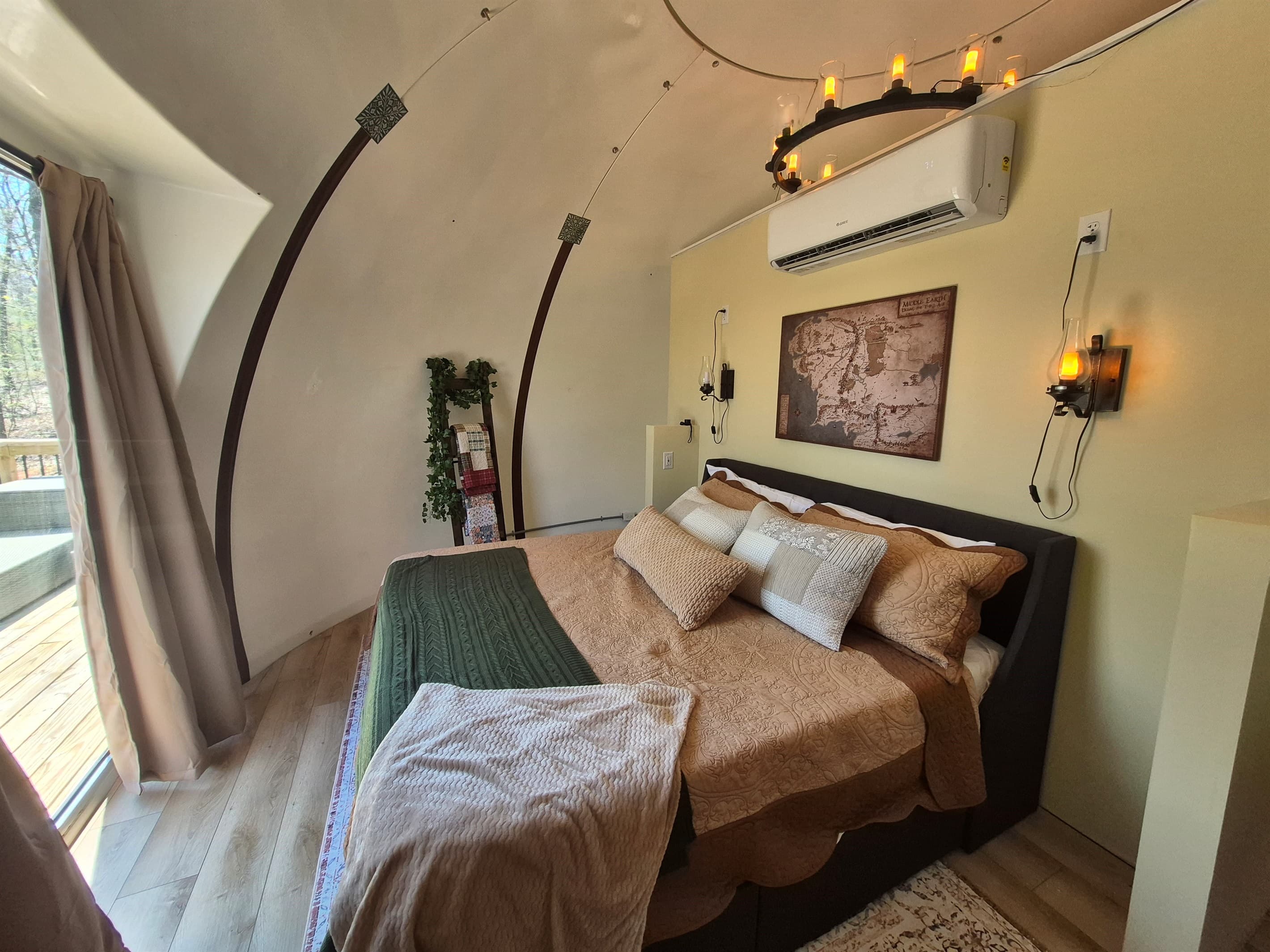 King bed with view out panoramic window to deck and woods beyond
