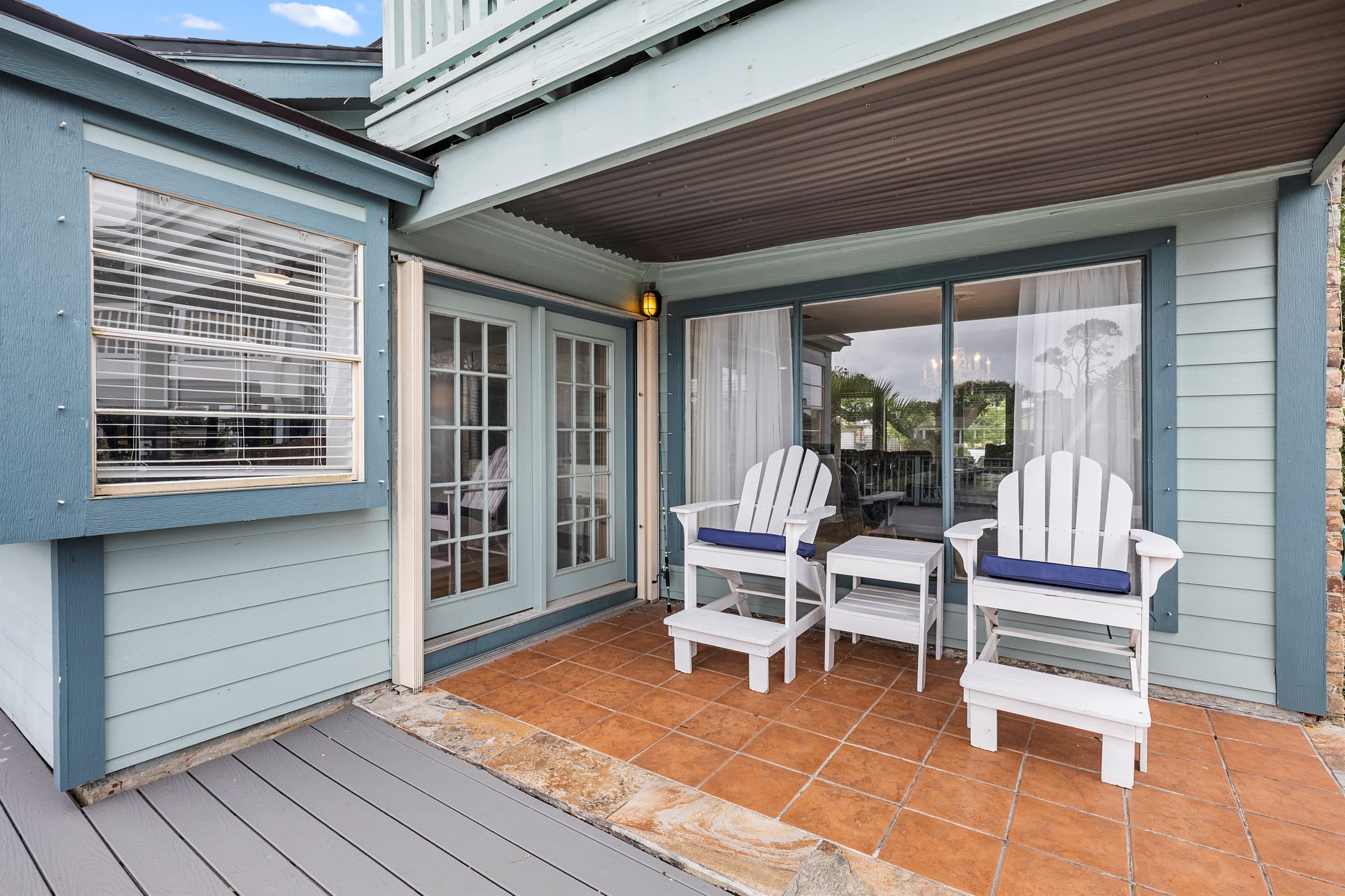 Covered lower deck at Lakeview Landing — shaded Adirondack seating steps from the sliding doors, perfect for relaxing after Moody Gardens or Schlitterbahn.