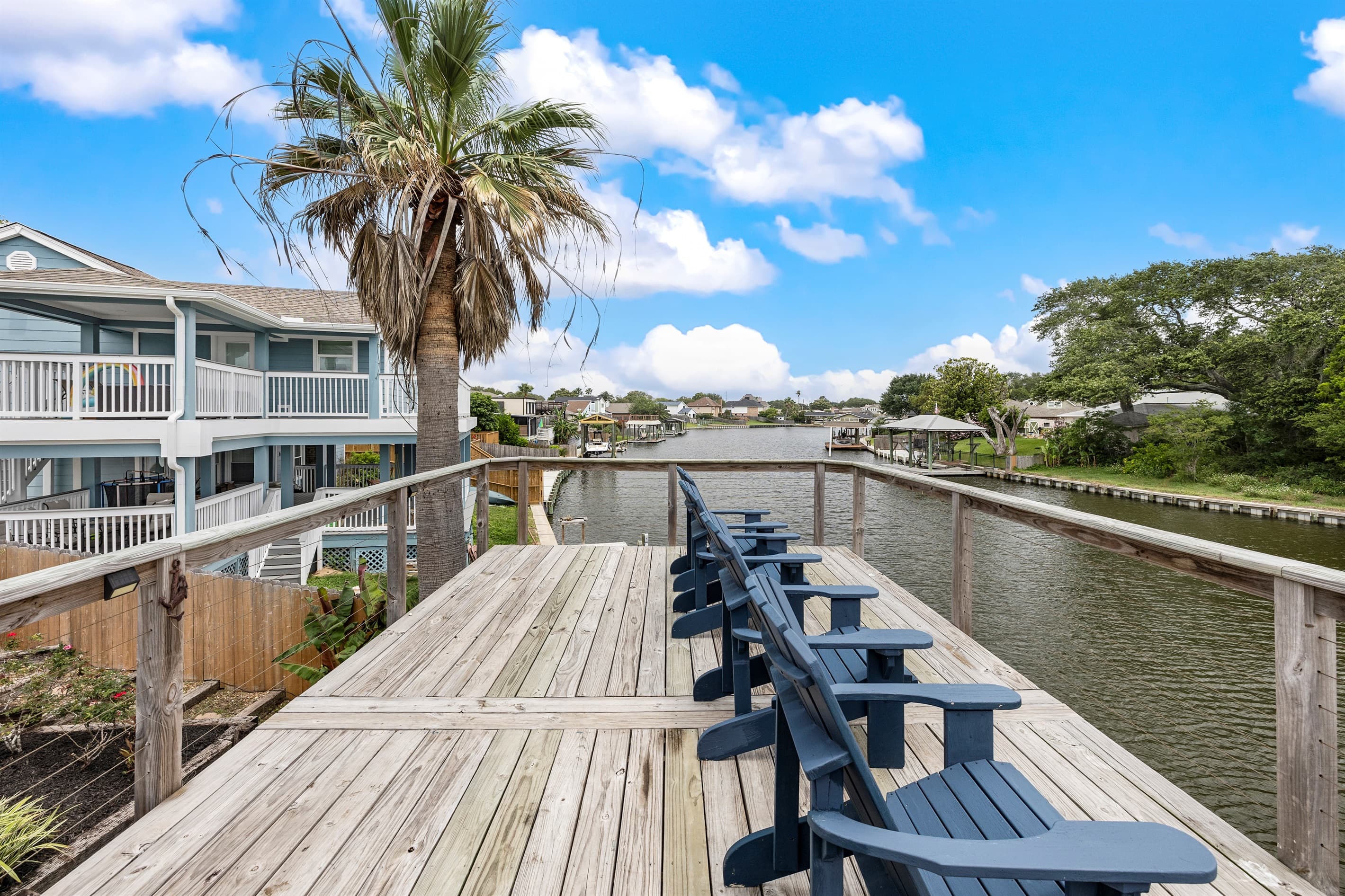 Dock seating at Lakeview Landing — Adirondack chairs at the water's edge on Madeline Lake, the perfect spot to feel the Galveston breeze.