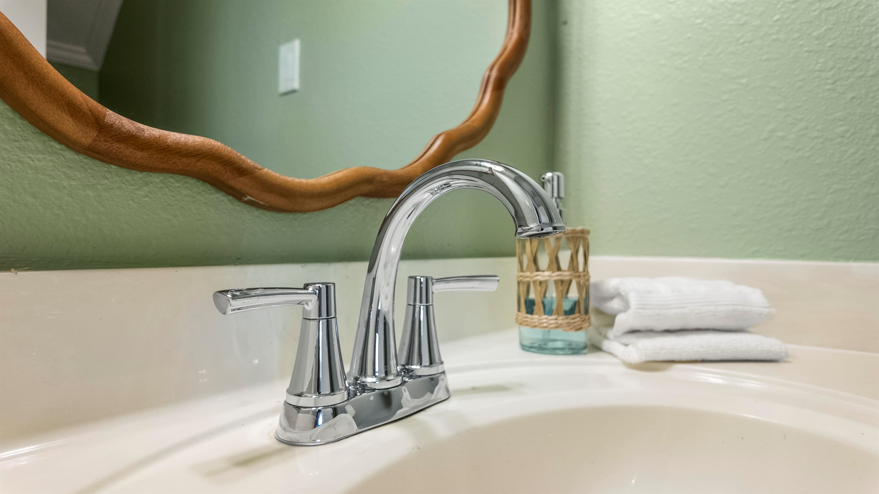 Chrome fixtures and a designer gold mirror bring style to the half bath at Lakeview Landing — thoughtful details in every room of this Galveston home.