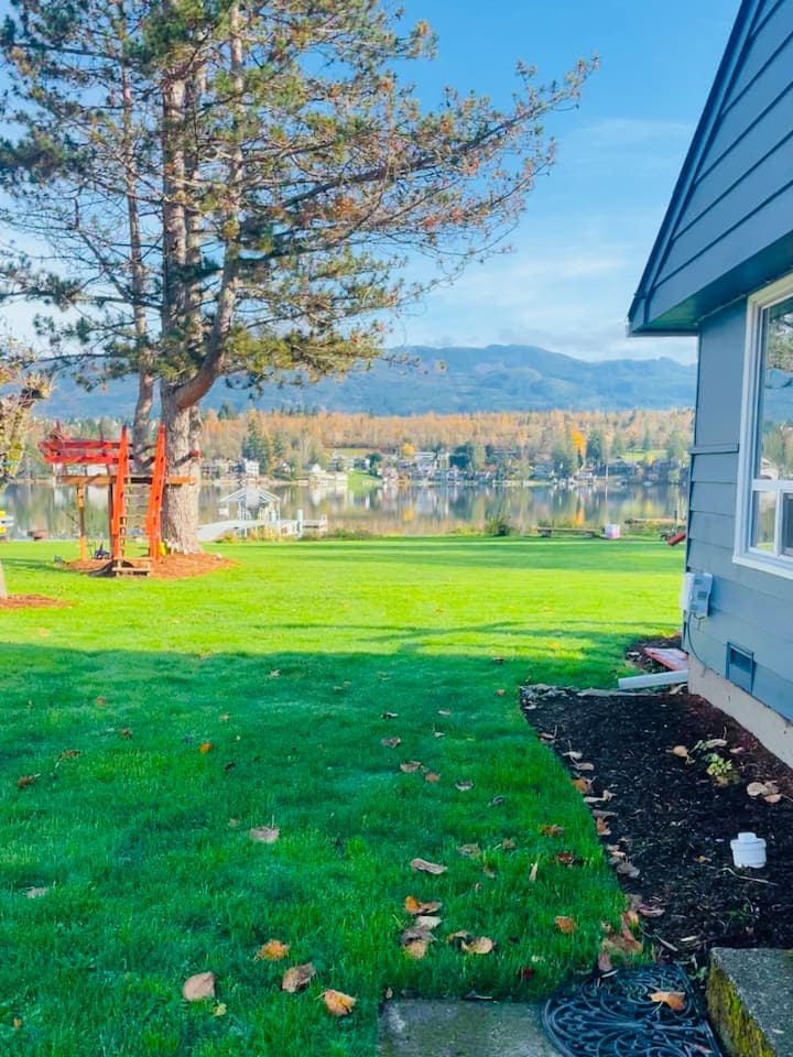 A bird-watching tower rises above a backyard that flows straight into the lake, with open views across the water and distant shoreline.