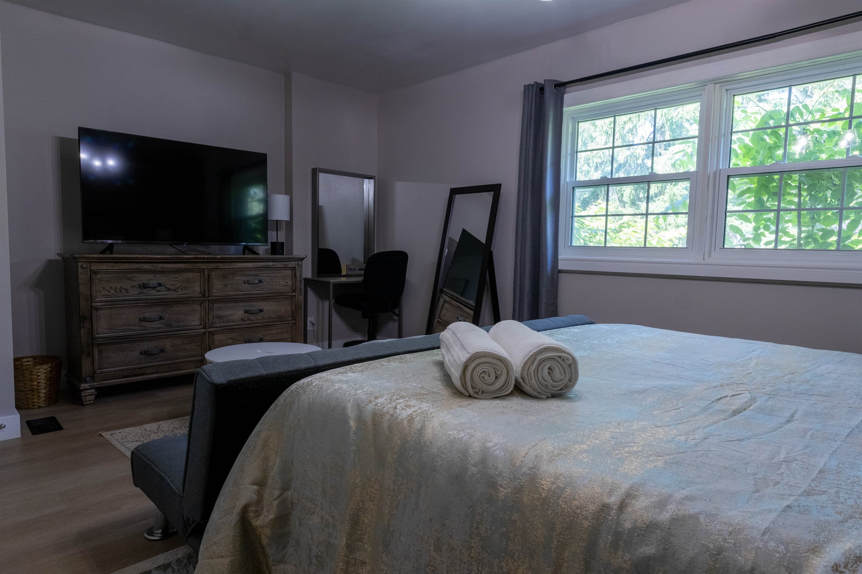 Your comfortable escape: primary bedroom with TV, pull-down couch, desk, soft carpet, dresser, closet, USB lamps, and cozy robes.