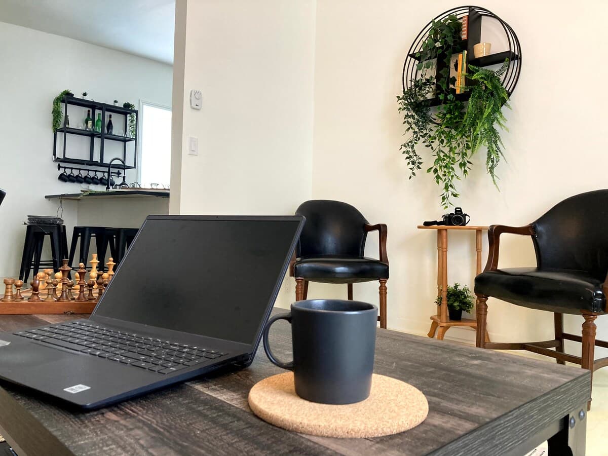 Bright and stylish living room with mid-century charm, leather sofa, smart TV, chic decor, and a cozy vibe—perfect for relaxing, working remotely, or enjoying a game night. Air-conditioned and filled with natural light for year-round comfort.