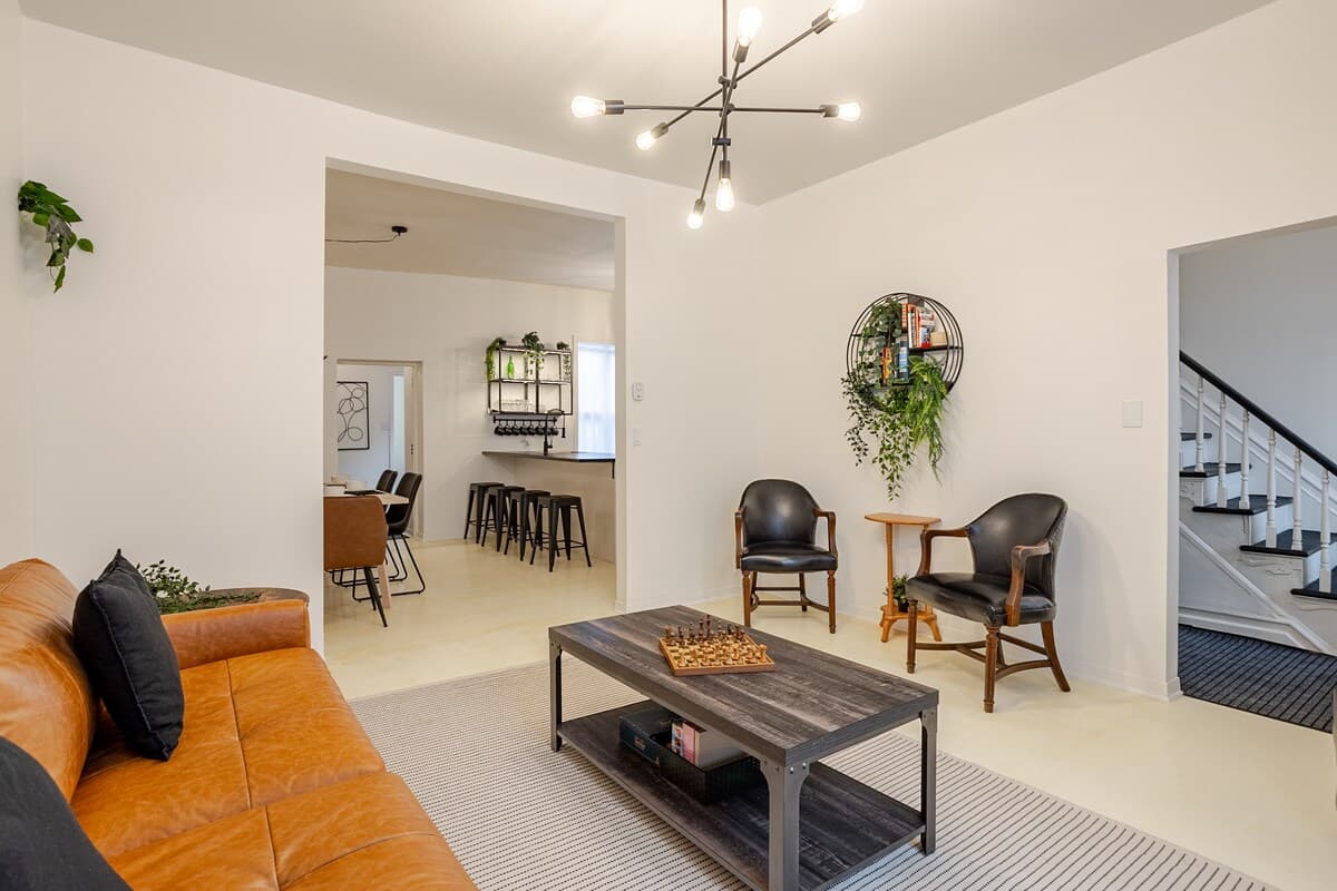 Bright and stylish living room with mid-century charm, leather sofa, smart TV, chic decor, and a cozy vibe—perfect for relaxing, working remotely, or enjoying a game night. Air-conditioned and filled with natural light for year-round comfort.