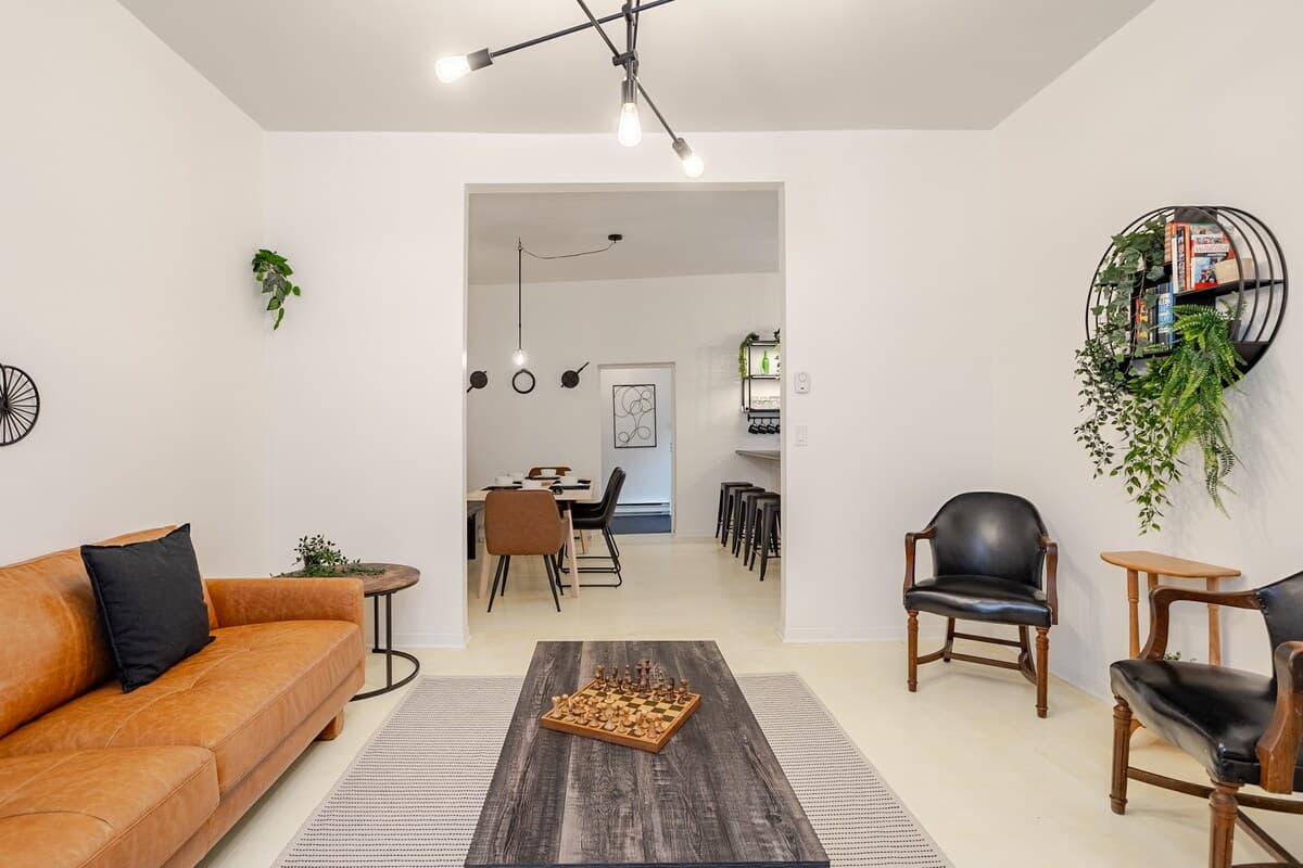 Bright and stylish living room with mid-century charm, leather sofa, smart TV, chic decor, and a cozy vibe—perfect for relaxing, working remotely, or enjoying a game night. Air-conditioned and filled with natural light for year-round comfort.