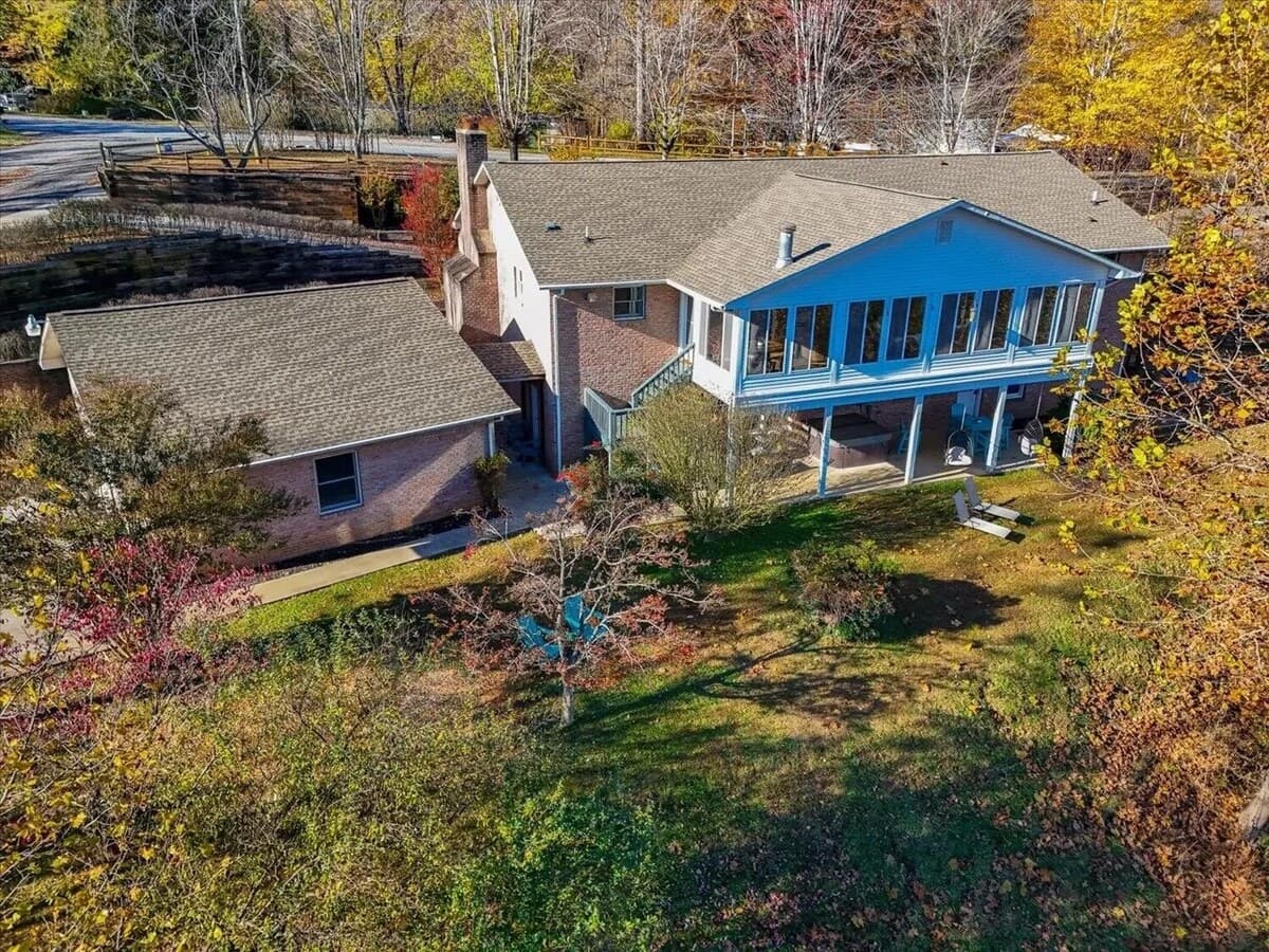 Rear aerial view — wraparound sunroom, covered patio, and big backyard.

Lake Front (Private dock) brick home, sunroom, wraparound deck, covered patio, two-story, large yard, group-friendly, spacious rental, family reunion, Smith Mountain Lake house.