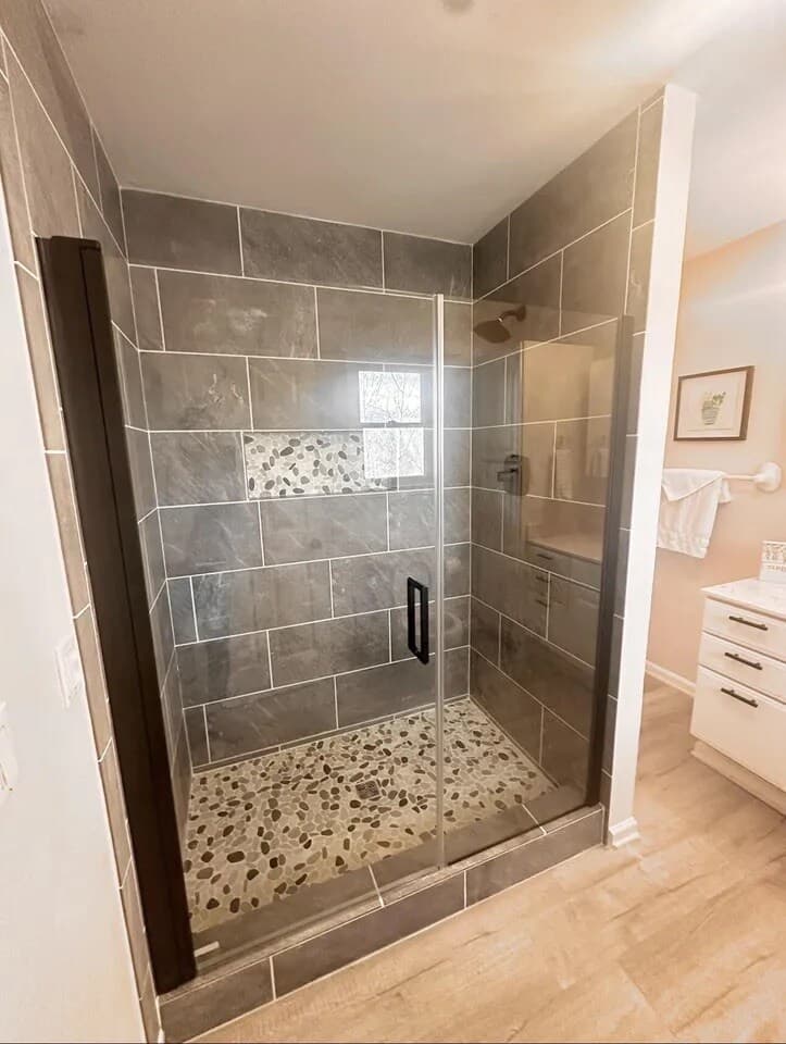 Tiled walk-in shower flows into bright, open living space.walk-in shower, slate tile, recessed niche, frameless glass, matte black hardware, bright natural light, cohesive design, coastal modern.