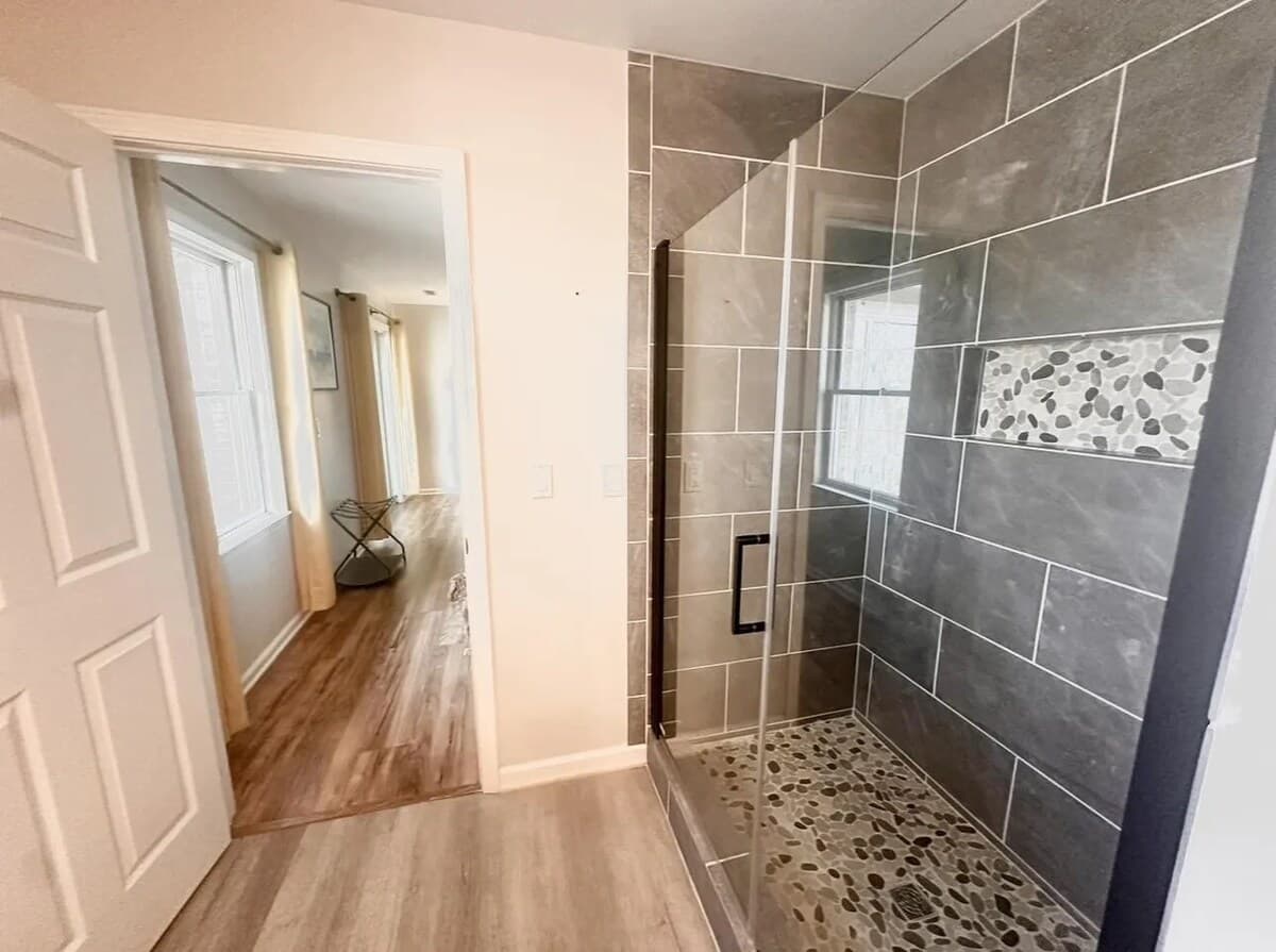 :
Spa-worthy walk-in shower — your private rinse-off after the dock. walk-in shower, frameless glass, slate tile, pebble mosaic floor, recessed niche, matte black fixtures, spa bathroom, custom tile work.
